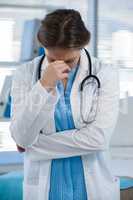 Worried doctor standing with hand on head