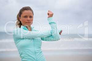 Portrait of woman performing stretching exercise on beach