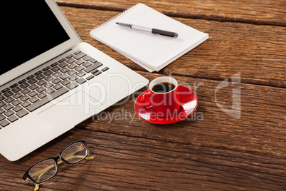 Laptop, spectacle and notepad with cup of coffee