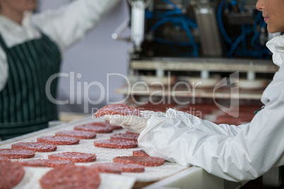 Female butcher processing hamburger patty