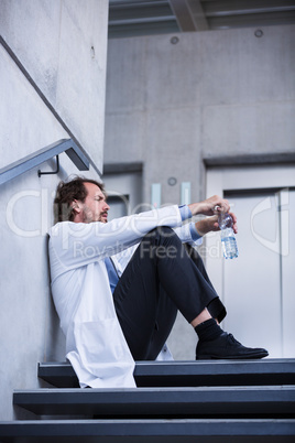Worried doctor sitting on stairs