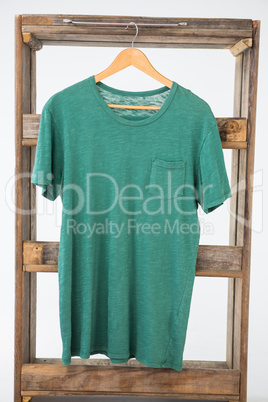 Green t-shirt hanging on wooden frame