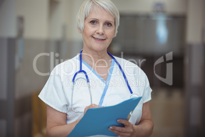 Portrait of female nurse writing on clipboard in corridor
