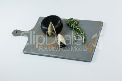 Black cheese with rosemary on chopping board