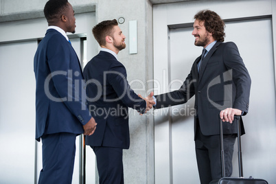 Businessmen shaking hands while waiting for elevator