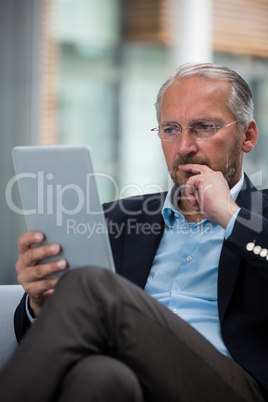 Thoughtful businessman holding a digital tablet