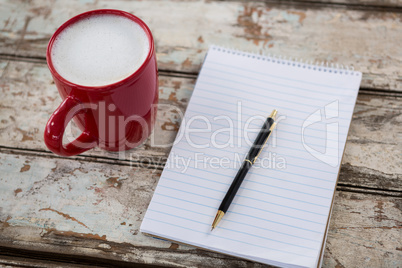 Cup of coffee with blank notepad and pen