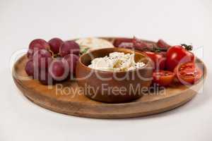 Crispy biscuits, cherry tomatoes, grapes and bowl of cheese on wooden board