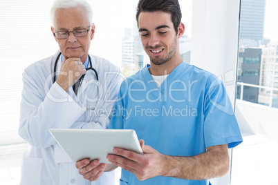 Surgeon and doctor discussing over digital tablet