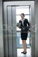 Businesswoman standing in an elevator holding a digital tablet