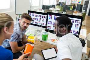 Graphic designers discussing over a container at their desk