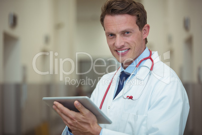 Portrait of male doctor using digital tablet in corridor