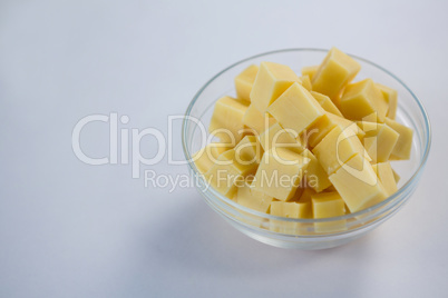 Cubes of cheese in a bowl against white background