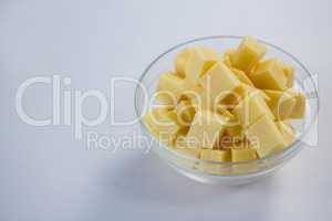 Cubes of cheese in a bowl against white background