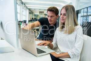 Graphic designers working over laptop at desk