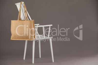 Beige fabric bag hanging on a white chair