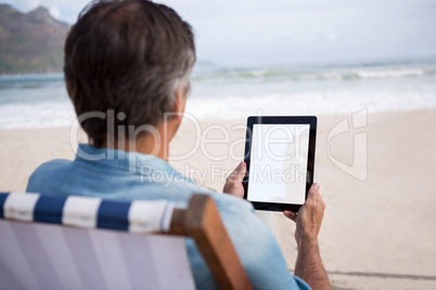 Rear view of man using digital tablet on beach