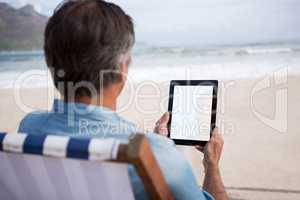 Rear view of man using digital tablet on beach