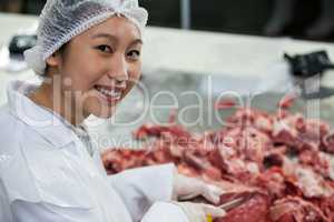 Female butcher cutting meat at meat factory