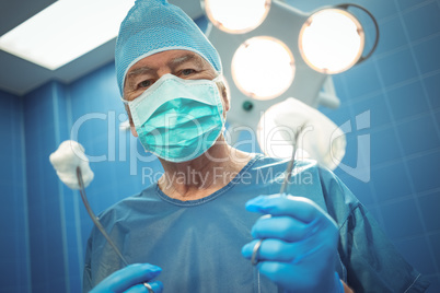 Portrait of male surgeon holding surgical tools in hand