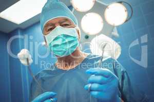 Portrait of male surgeon holding surgical tools in hand