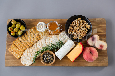 Variety of cheese with olives, peach, honey, rosemary, walnuts and crackers