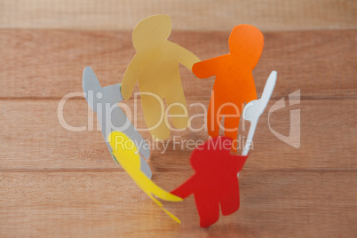 Multicolored paper cut outs forming a circle on wooden background