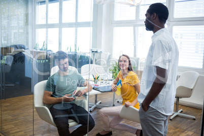 Graphic designers interacting with each other while working at desk