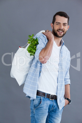 Man in light blue shirt carrying a grocery bag