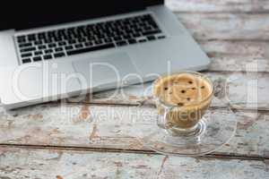 Cup of coffee and laptop on wooden table