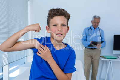 Portrait of boy flexing his biceps in the clinic