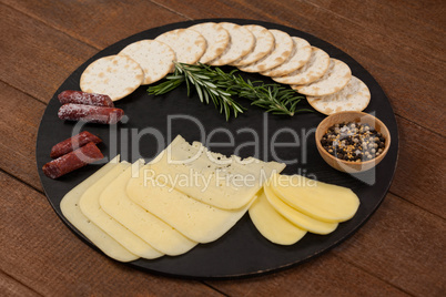 Cheese, rosemary, sausages, spices, biscuits and potatoes on slate board