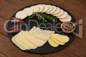 Cheese, rosemary, sausages, spices, biscuits and potatoes on slate board