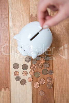 Hand inserting a coin into the piggy bank