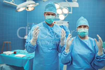 Portrait of male and female surgeon standing in operation theater