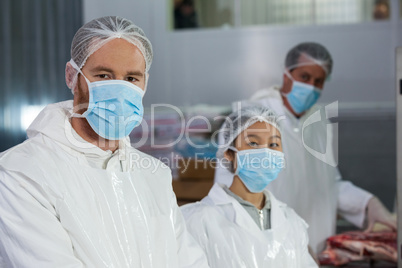 Butchers in protective workwear at meat factory