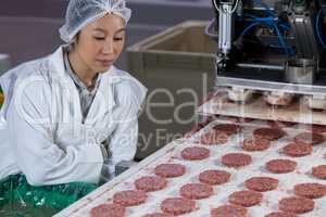 Female butcher processing hamburger patty