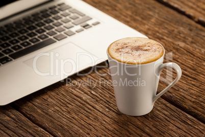 Laptop and cup of coffee on wooden table