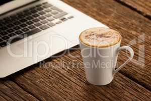 Laptop and cup of coffee on wooden table