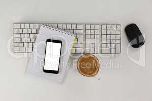 Cup of coffee with keyboard, mobile phone and mouse