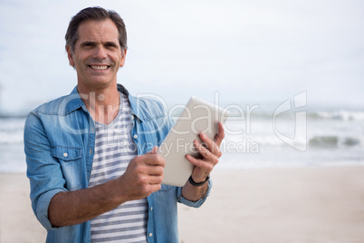 Portrait of man using digital tablet on beach