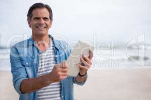 Portrait of man using digital tablet on beach