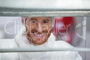 Smiling butcher standing in meat factory