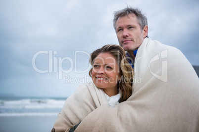 Happy couple wrapped in shawl
