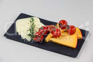 Cheese with tomatoes and rosemary on slate board