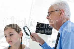 Doctor examining patient ear by using magnifying glass