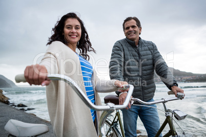 Portrait of happy couple standing with bicycle