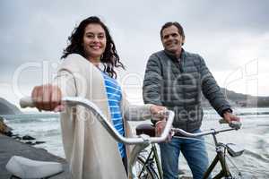 Portrait of happy couple standing with bicycle