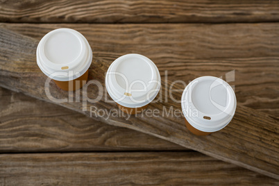 Disposable coffee cups on wooden plank