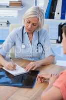 Doctor writing a prescription for her patient in medical office
